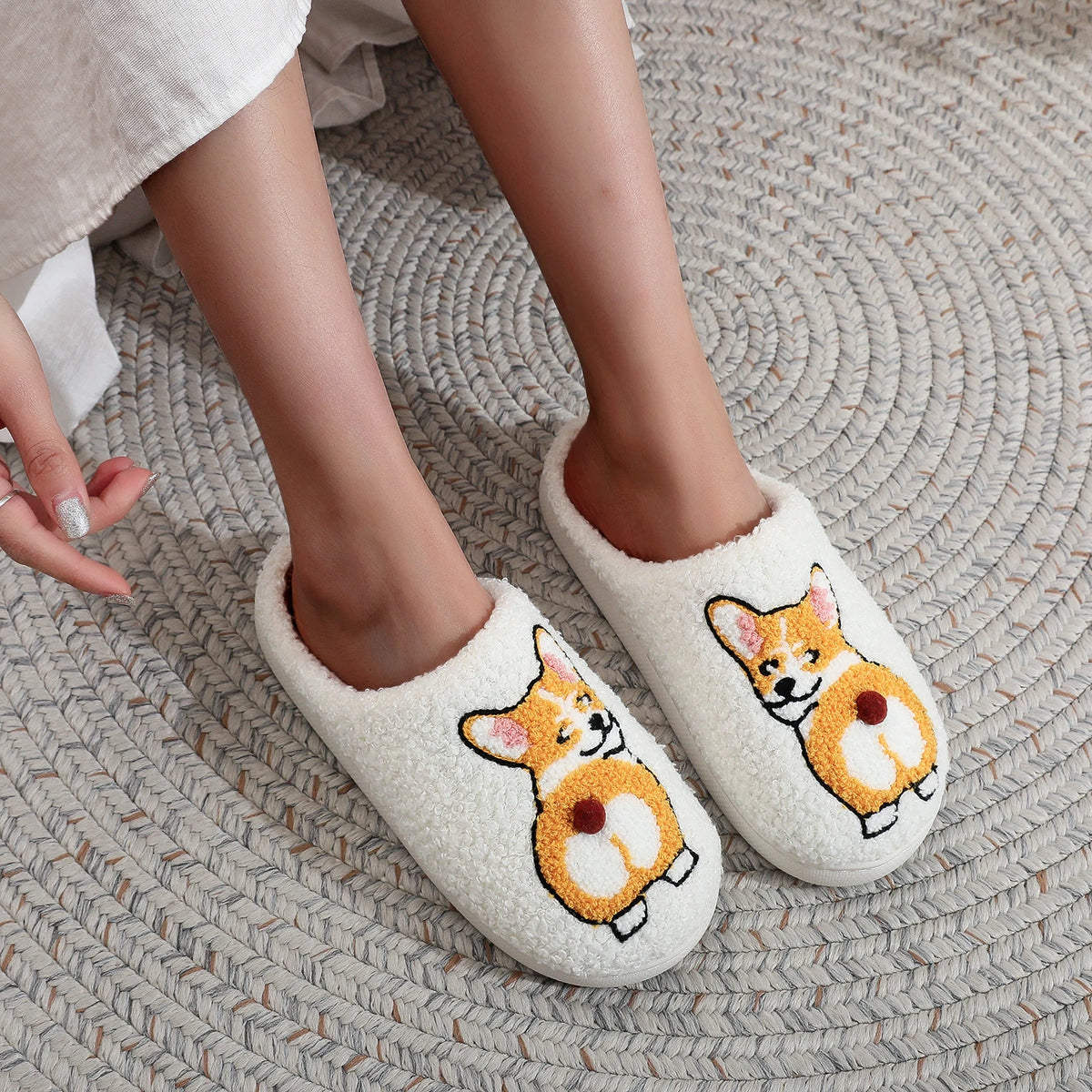 White slippers with corgi dog illustrations worn on a textured rug