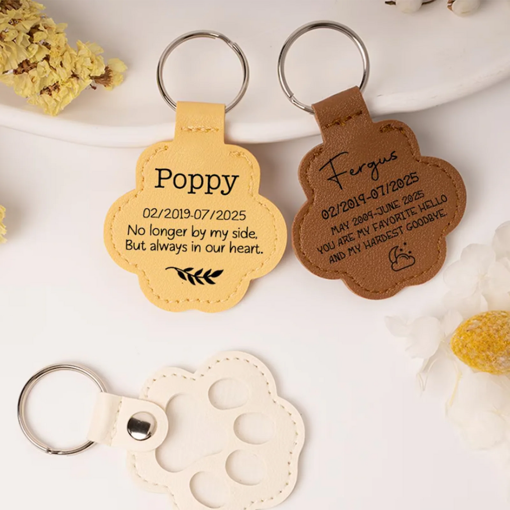 Three leather keychains with engraved text on a white surface with flowers.