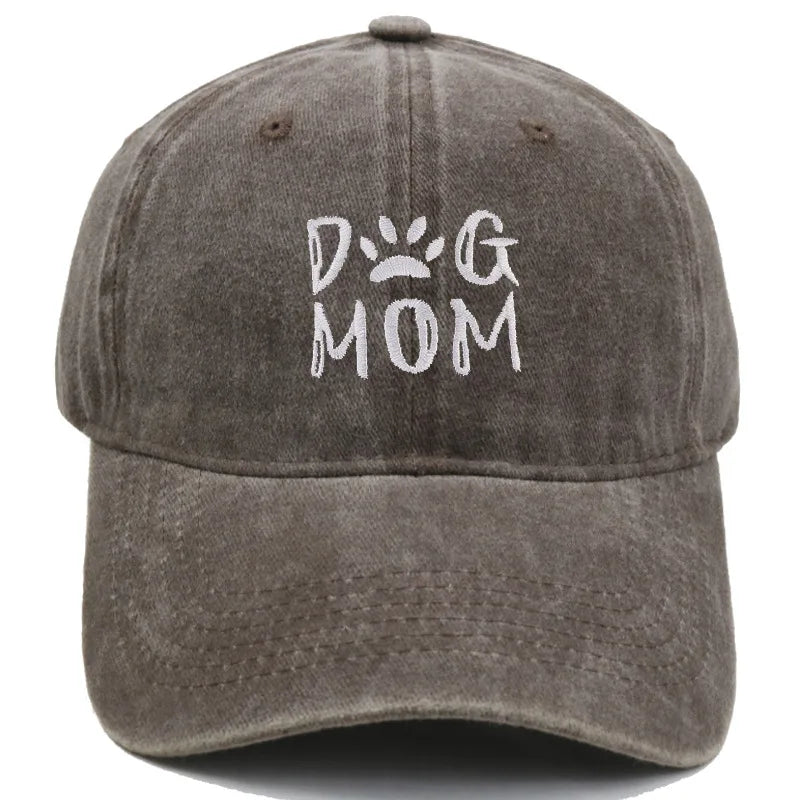 A washed dark gray baseball cap featuring white embroidered text that reads 'DOG MOM' with a paw print icon, shown against a plain white background.
