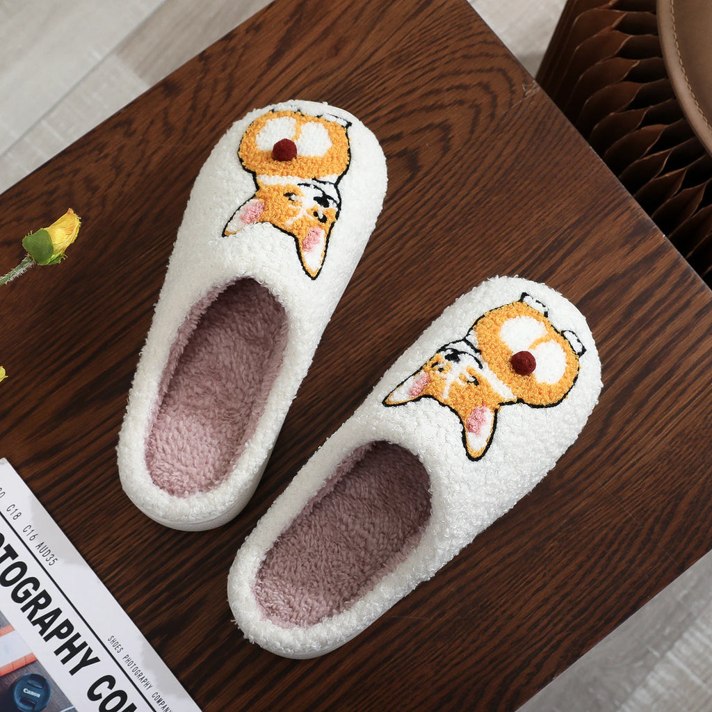 Pair of white slippers with cartoon corgi design on a wooden surface
