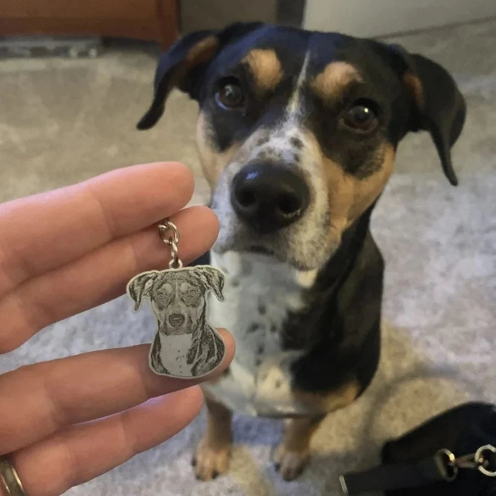 Dog looking at a keychain with a dog's face on it held by a person.