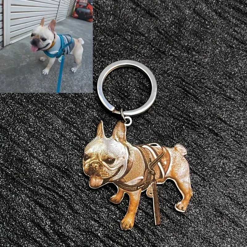 Gold bulldog keychain on a textured surface with a small inset photo of a dog wearing a blue harness.
