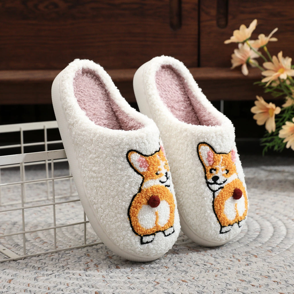 Pair of white slippers with corgi design on a textured surface.