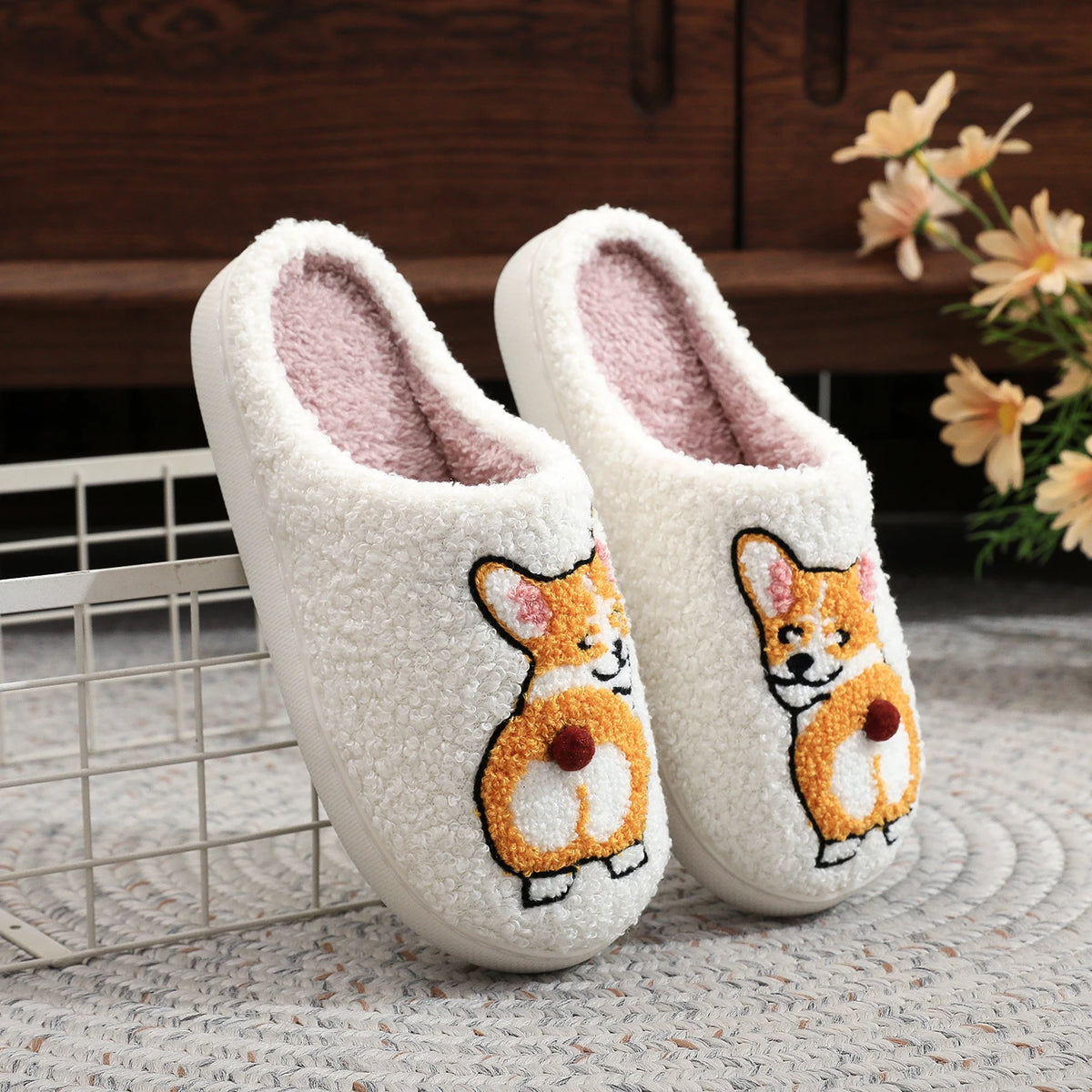 Pair of white slippers with corgi design on a textured surface.